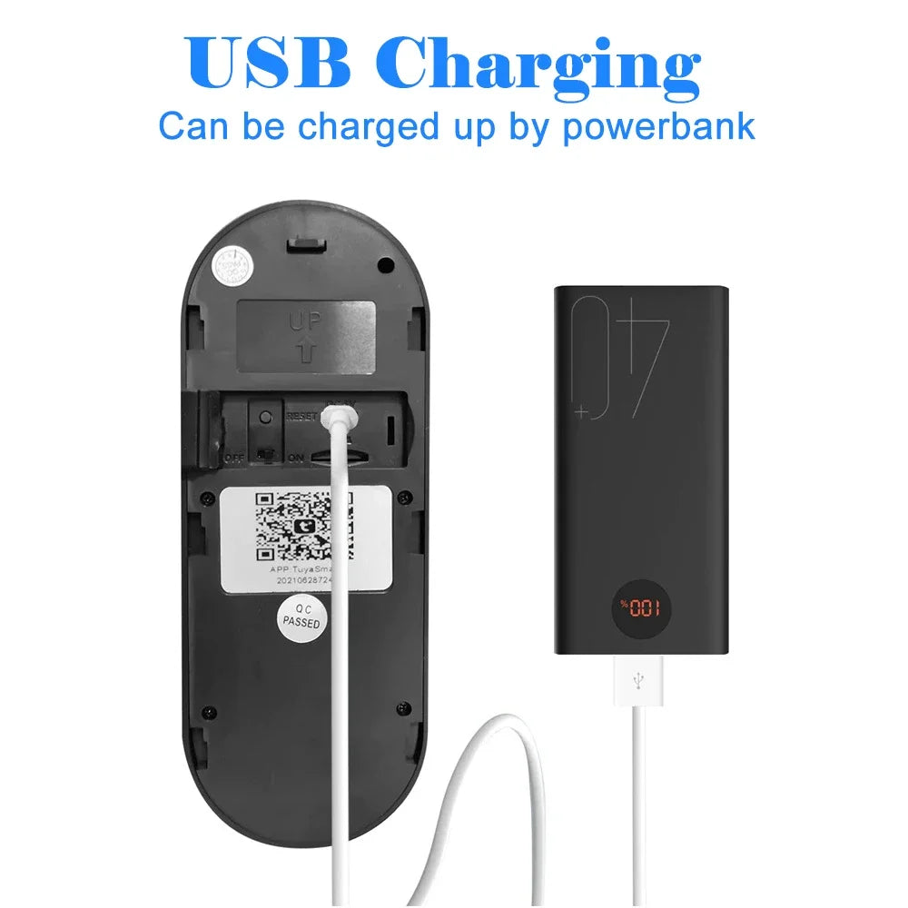 Black wireless smart doorbell charging via a white USB cable connected to a black power bank.