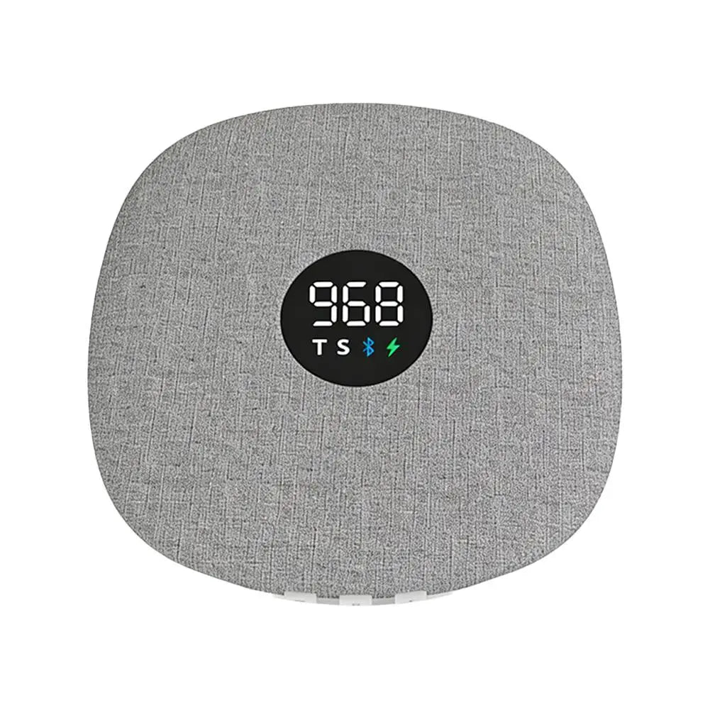 Grey, fabric-covered wireless under-pillow Bluetooth speaker with a central digital display and charging indicator.