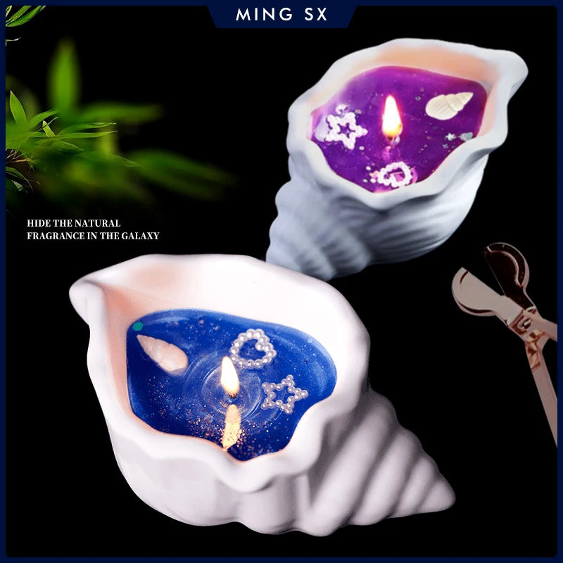 Two white shell-shaped candles with purple and blue wax, decorated with star and heart charms, on a black background.