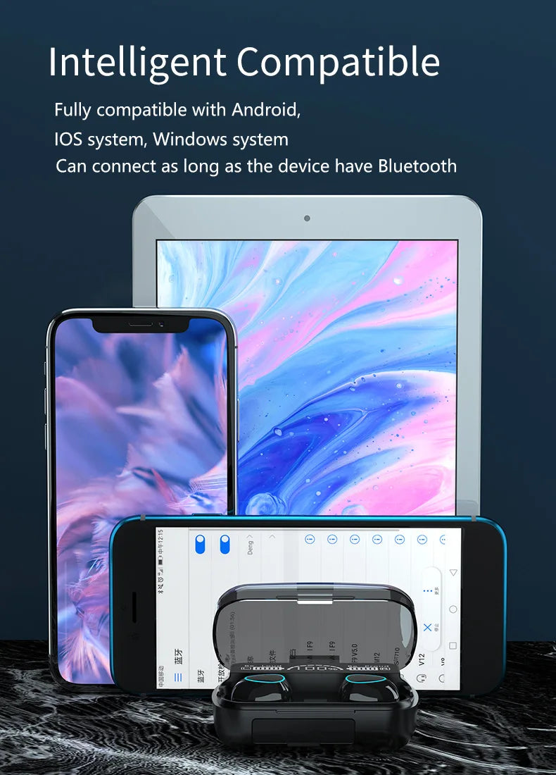Black wireless earbuds in a digital charging case in front of a smartphone and tablet on a dark marble surface.