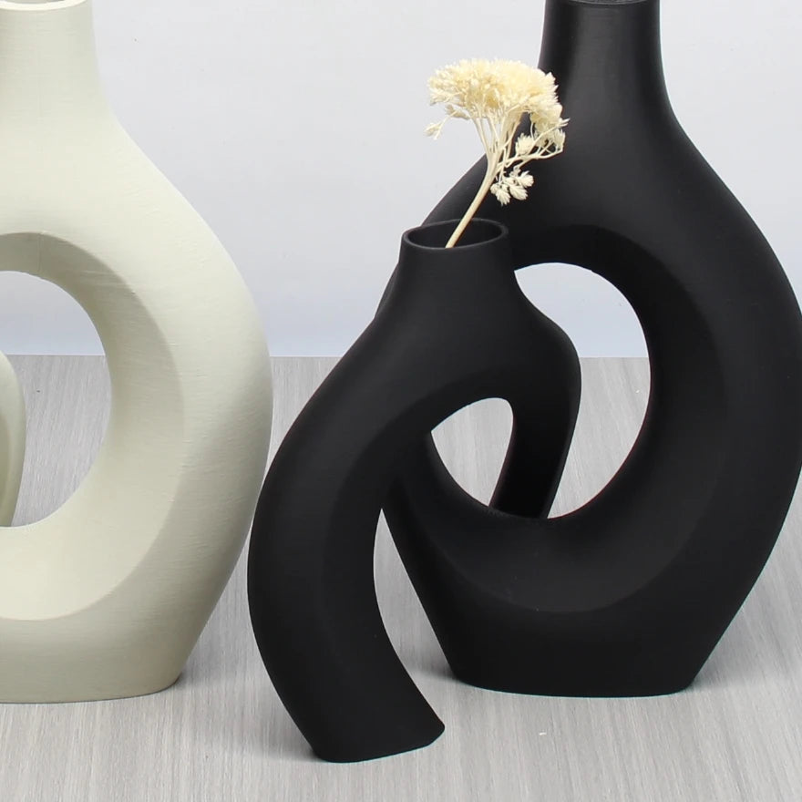 Set of sculptural, bohemian-style ceramic vases in matte black and cream, featuring abstract, hollow circular shapes.