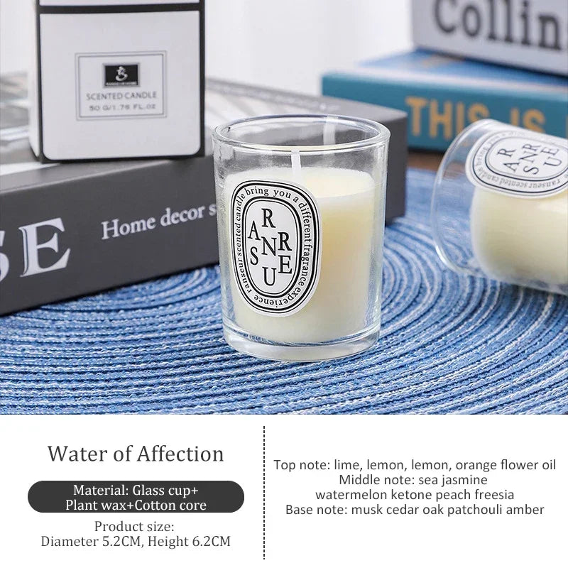 Small scented candle in a glass votive with a minimalist white oval label, resting on a blue woven placemat.