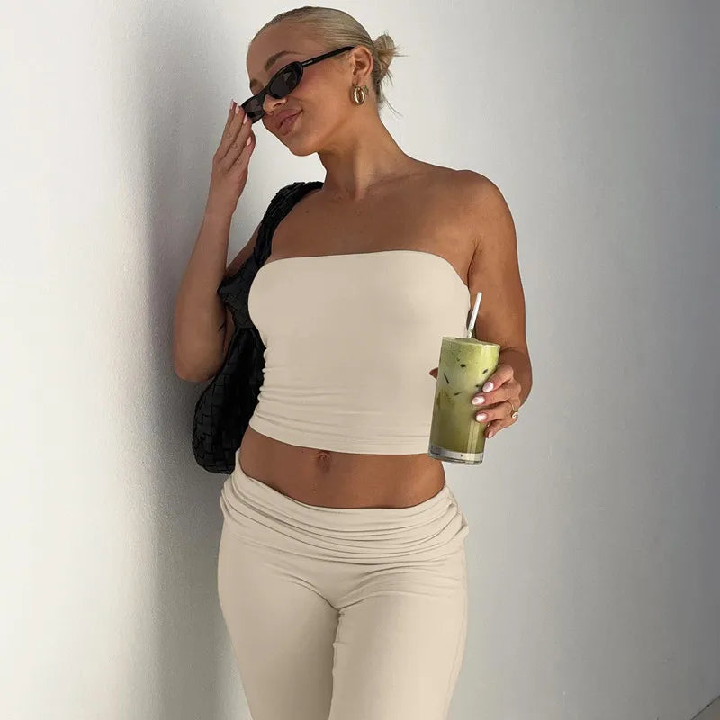 Woman wearing a cream strapless tube top and matching low-rise trousers with a gathered waistband.