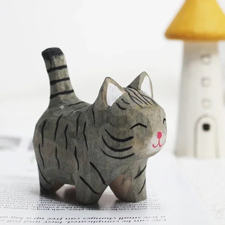 Small hand-carved wooden grey tabby cat figurine with a painted pink nose, standing with tail raised.