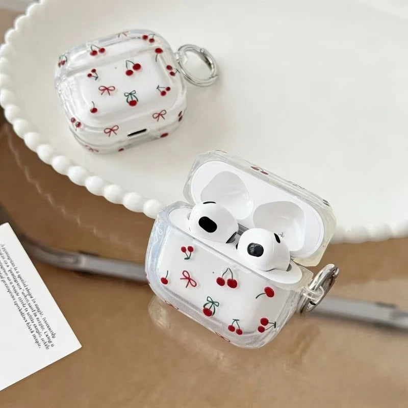 Clear AirPods 3 case featuring a red cherry and ribbon pattern, complete with a side attachment ring.