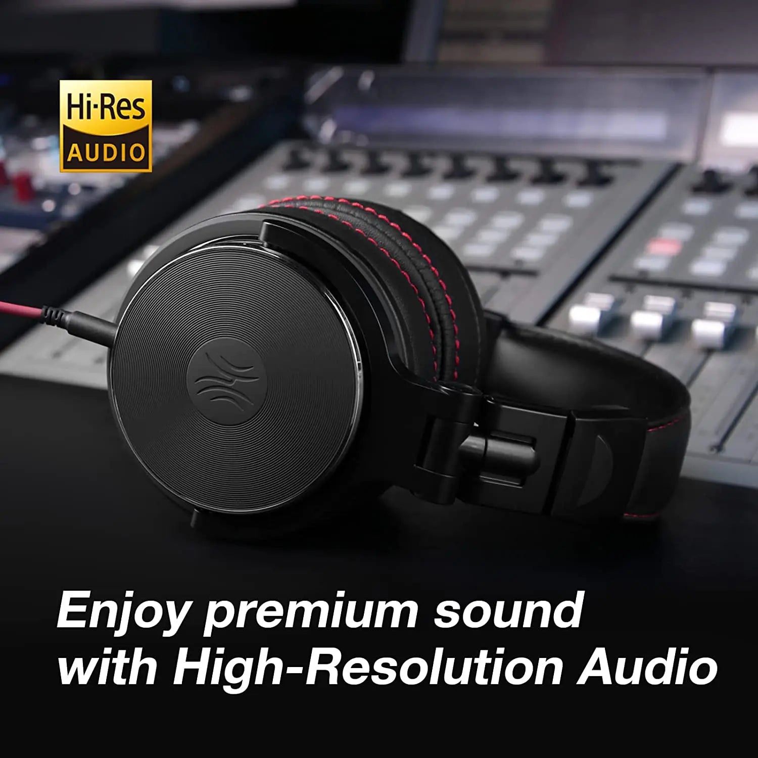 Black wired over-ear studio headphones with red stitching, featuring Hi-Res Audio certification on a mixing desk.