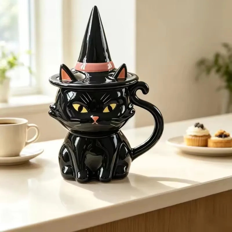 Black ceramic cat mug with a tail handle and a matching witch hat lid with a pink band.