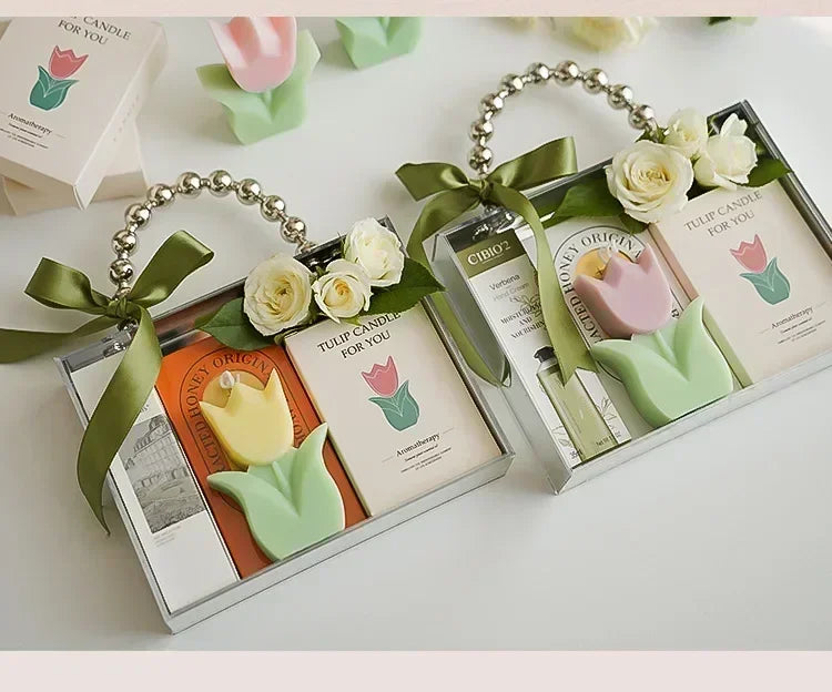 Gift sets with tulip-shaped candles, hand cream, and floral decor in clear bags with pearl-effect handles and ribbons.