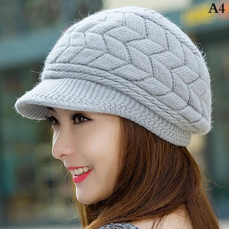 A woman wearing a grey, thermal-lined knitted winter hat with a textured chevron pattern and a small peak.