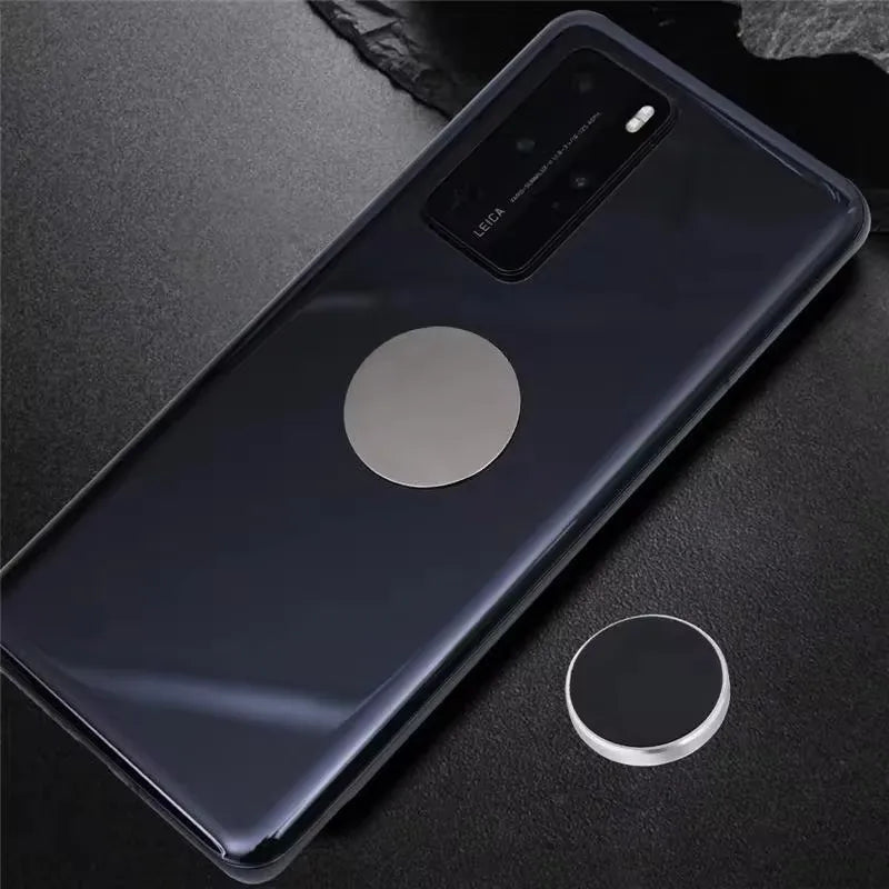Glossy black smartphone with a metallic silver circular magnetic plate attached to the back, plus a matching spare disc.