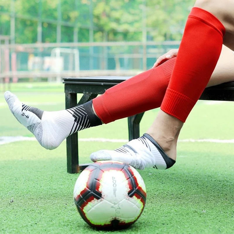 Bright red sports calf sleeves worn over white and black patterned football socks with a soccer ball.