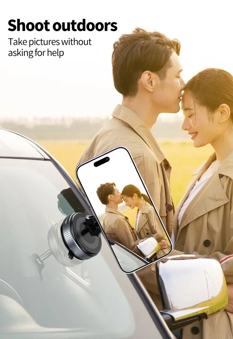 Black magnetic phone mount attached to a car windshield, holding a smartphone with a photo of a couple on screen.