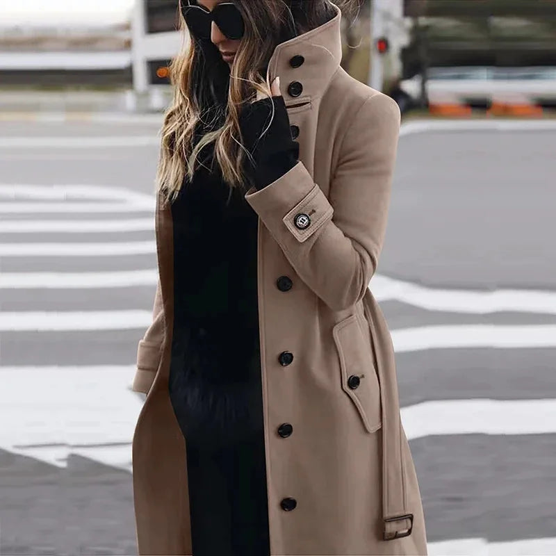 Camel-coloured, long-line tailored coat with a high collar, black button front, and cuff detailing.