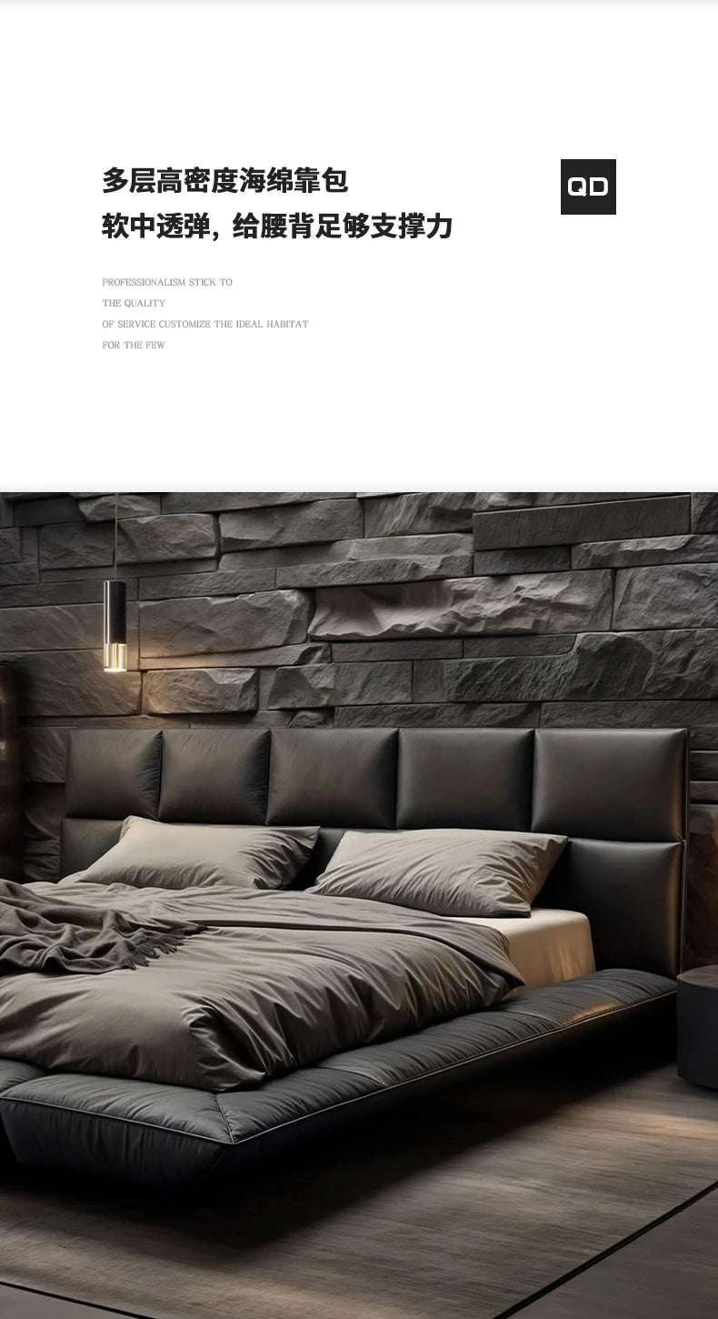 Modern floating king-size bed in dark grey leather with a wide, cushioned panelled headboard against a stone wall.