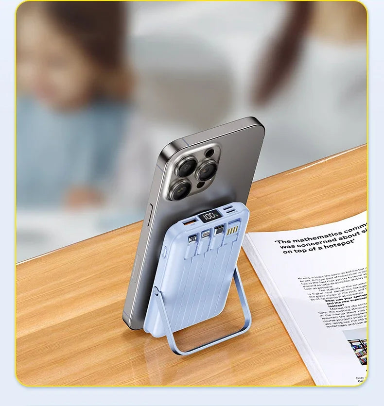 Light blue magnetic power bank with integrated cables, digital battery display, and folding stand, charging a smartphone.