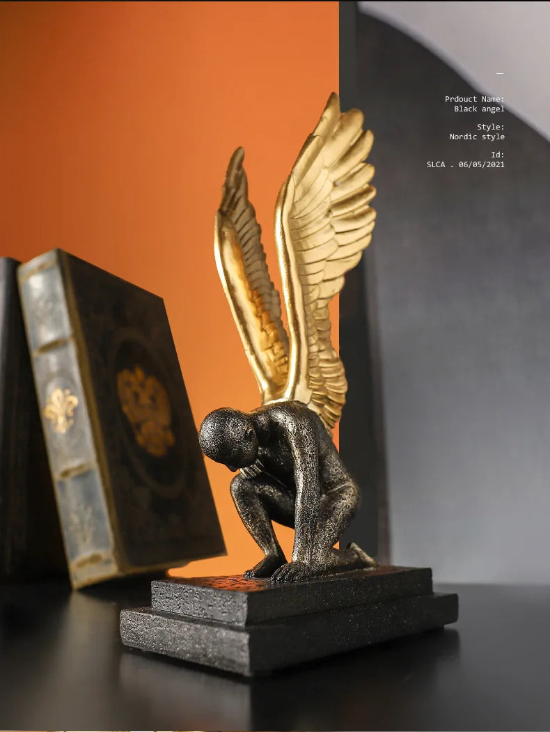 Nordic-style sculpture of a crouching figure with textured black body and striking gold wings on a black base.
