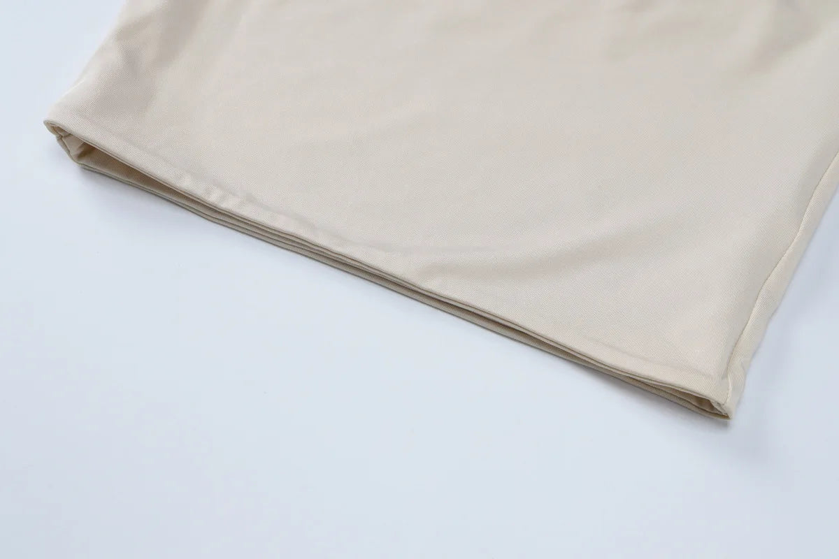 Close-up of a plain, smooth beige fabric hem showing a clean, folded finish on a white background.