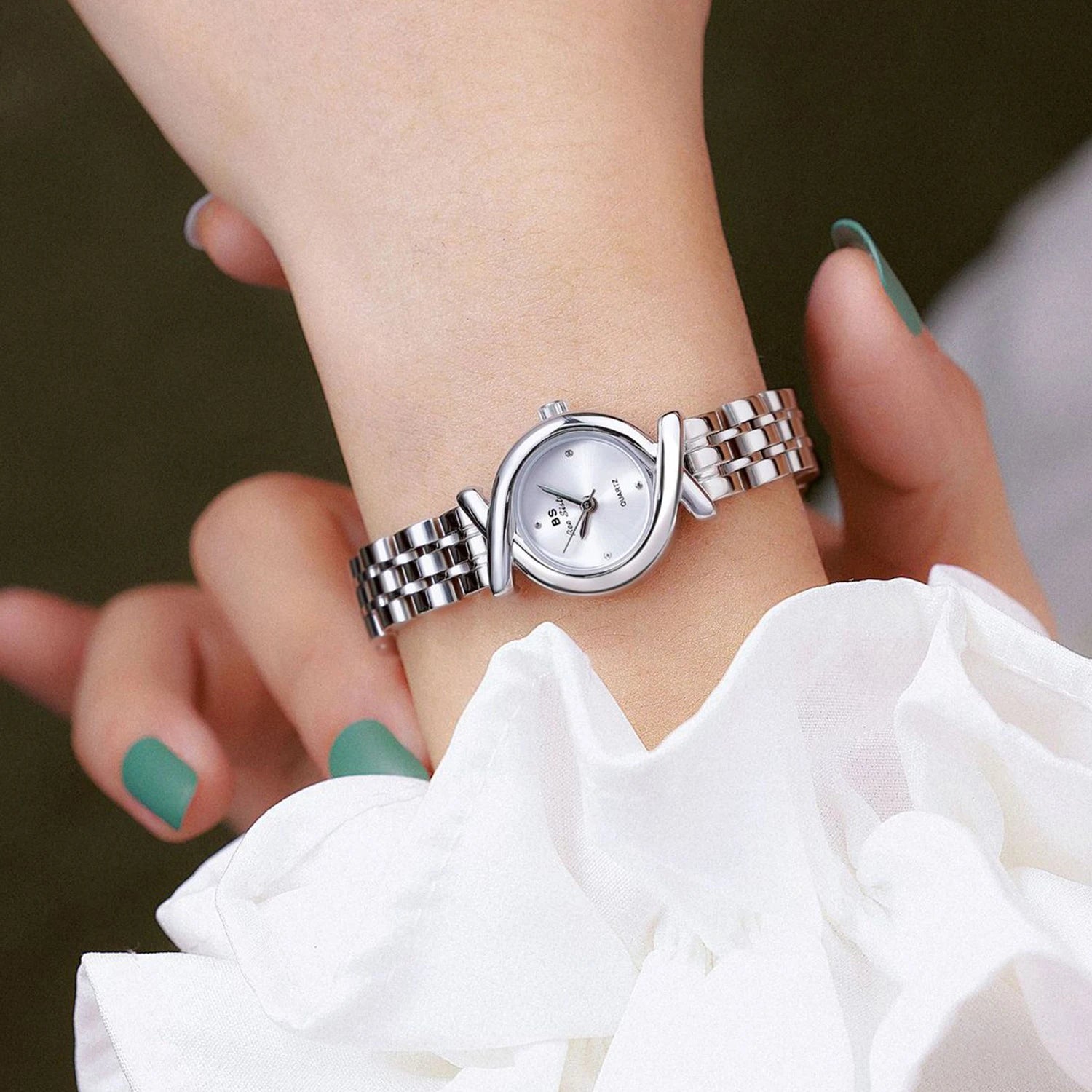 Elegant silver-tone quartz watch with a slim linked bracelet and a unique crossover frame on the wrist.