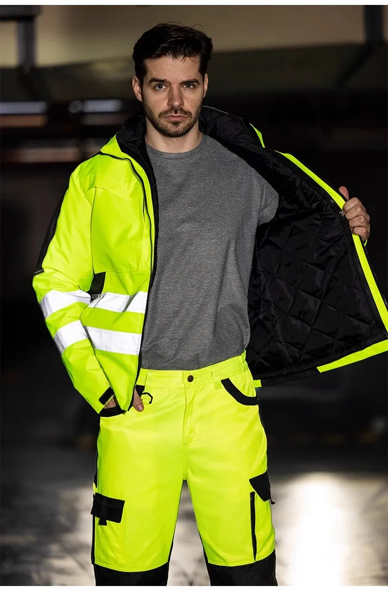 A man wearing a 3-in-1 hi-vis yellow waterproof jacket with reflective stripes and matching trousers with black accents.