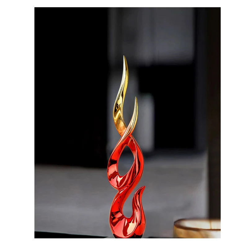 A modern, abstract resin ornament featuring smooth, flowing flame-like curves in a polished red and gold finish.