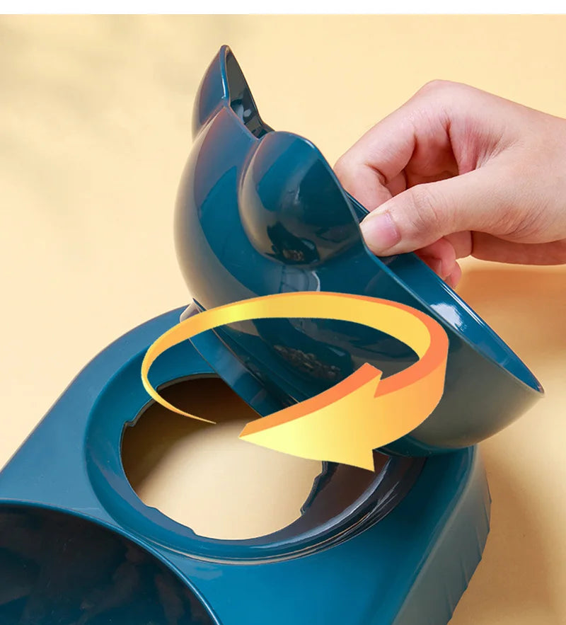 A hand lifting a dark teal, cat-ear-shaped pet food bowl from its base, indicated by a circular yellow arrow graphic.