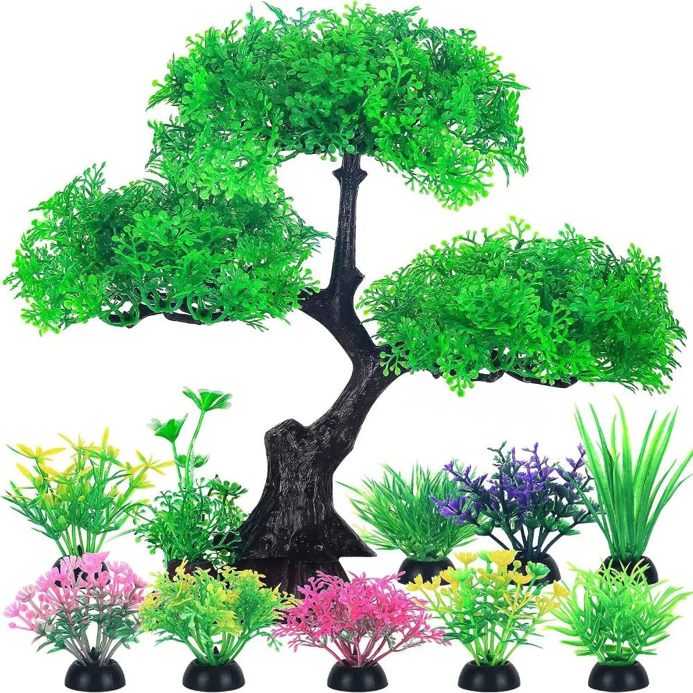 A central artificial bonsai tree with green leaves and a black base, surrounded by various small, colorful aquatic plants.