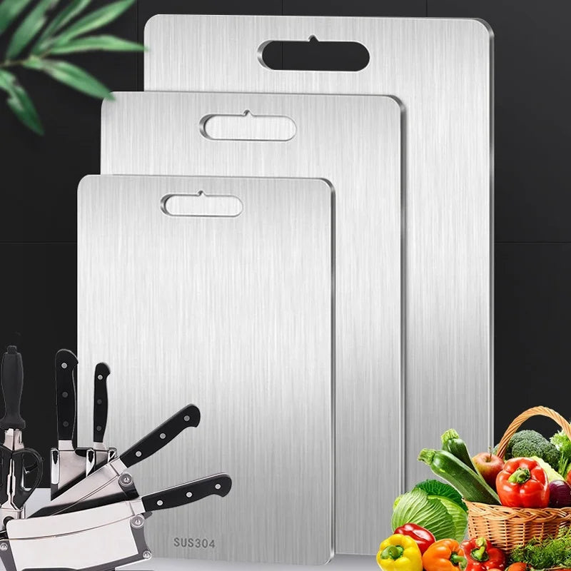 Three stainless steel cutting boards in different sizes, with knives and vegetables.