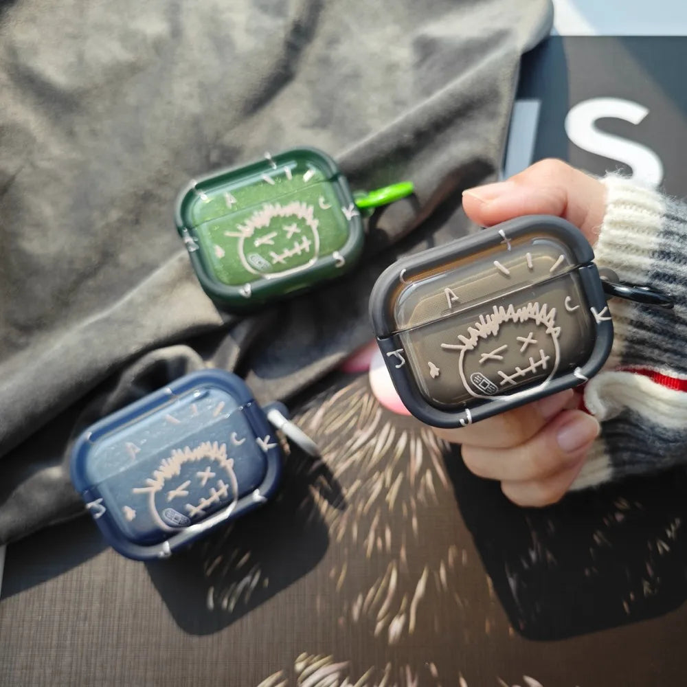 Graphic print silicone cases for AirPods Pro in black, green, and navy, featuring a stitched face design.