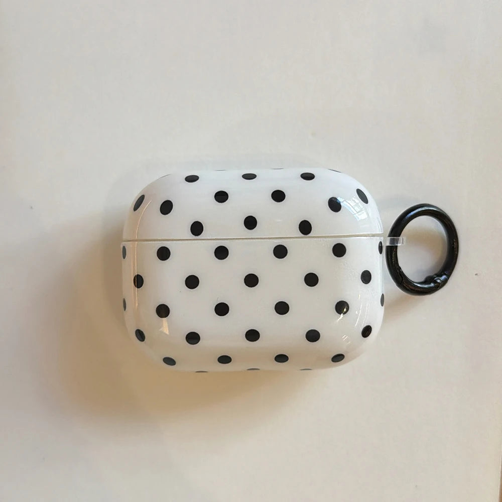 White and black polka dot glossy hard-shell case for Apple AirPods Pro, featuring a side attachment ring.