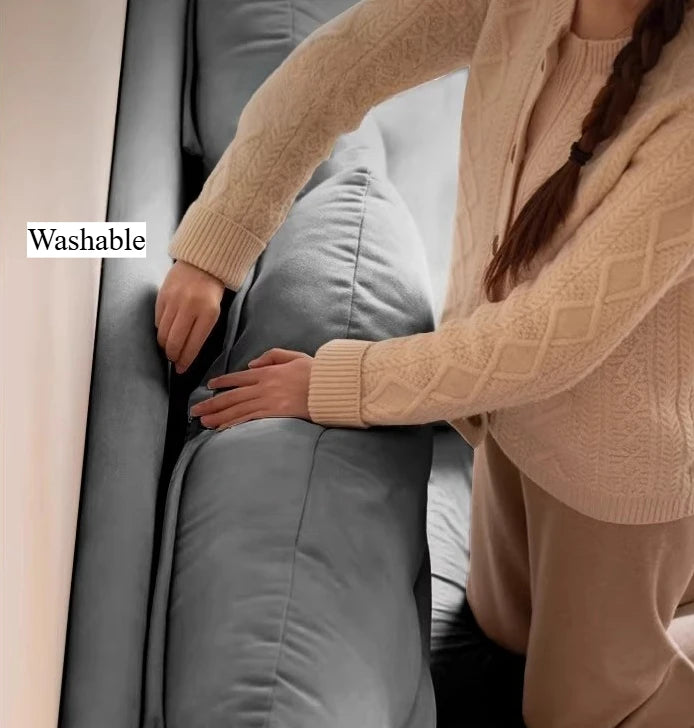 Close-up of a modern grey upholstered double bed, showing a person removing the washable fabric headboard cover.