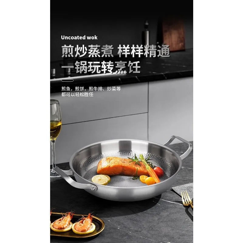 An uncoated stainless steel wok with two handles rests on a dark countertop, containing a cooked fish fillet and vegetables.
