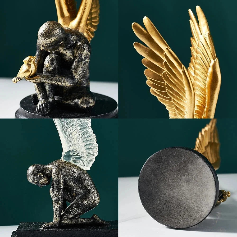 Ornate resin statue of a kneeling winged figure in dark rustic grey with detailed gold wings and a small golden bird.