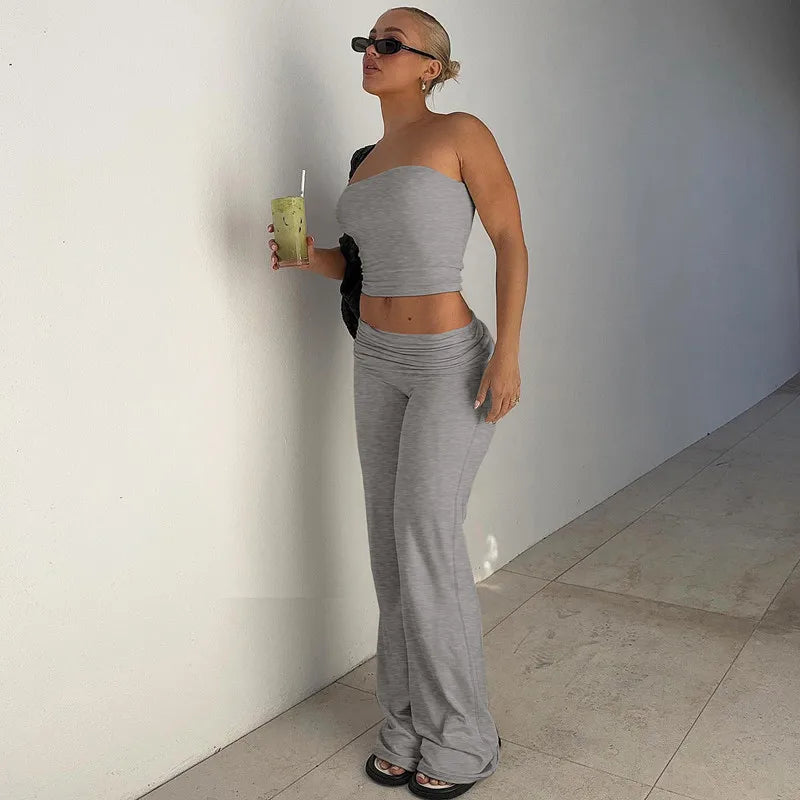 A woman wearing a grey strapless crop top and matching low-rise flared trousers in soft, stretchy fabric.