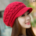 A woman wearing a cosy red knitted thermal hat with a peak and textured braided pattern.