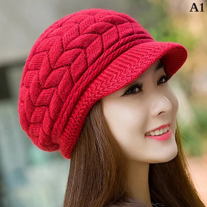 A woman wearing a cosy red knitted thermal hat with a peak and textured braided pattern.