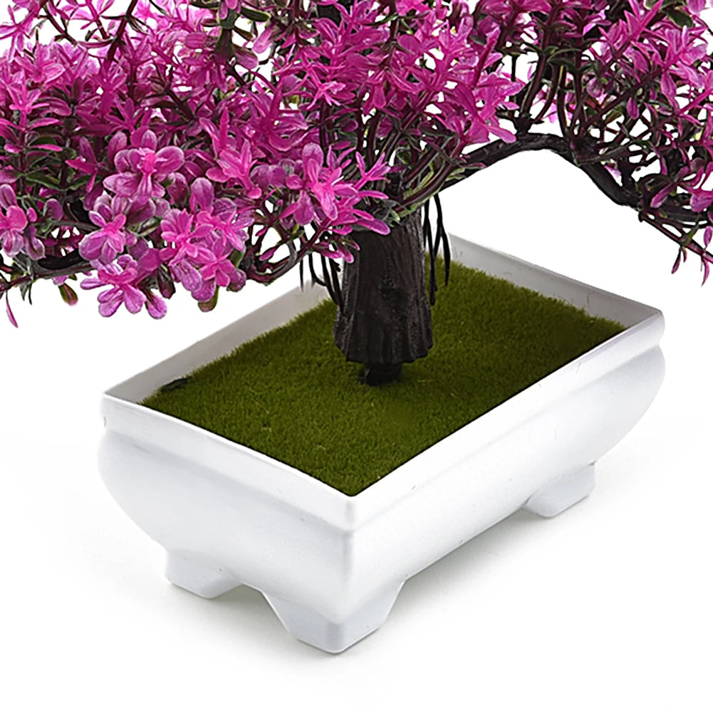 Artificial bonsai tree with vibrant magenta leaves in a white, rectangular ceramic pot with faux green moss.