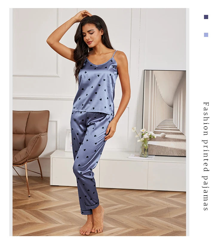 Woman wearing a blue satin pyjama set with black heart print, featuring a camisole top and matching trousers.