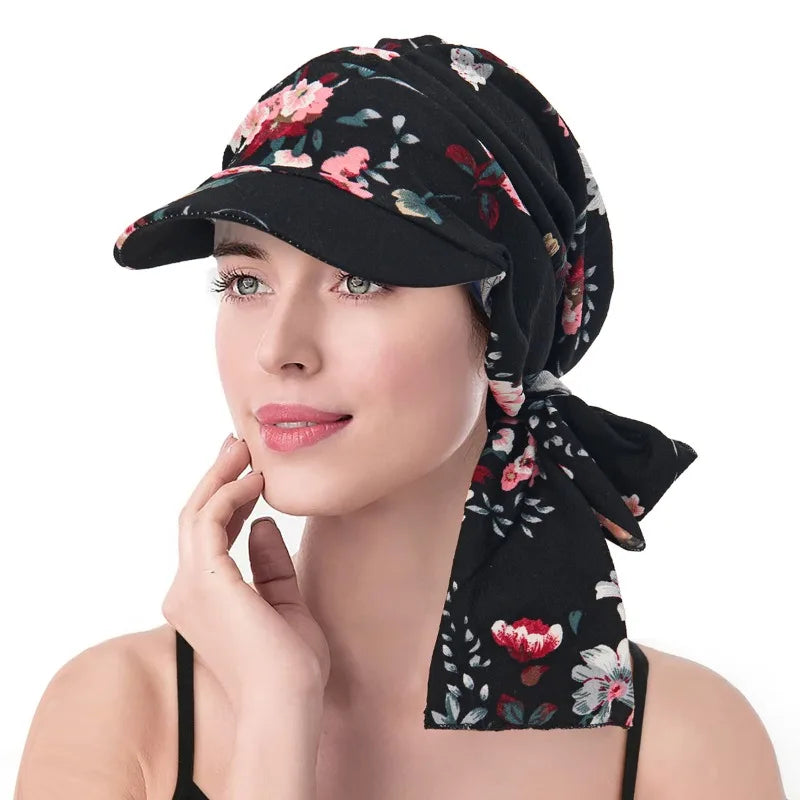 A woman wearing a black headscarf hat featuring a pink and white floral print and a practical, matching stiff brim.