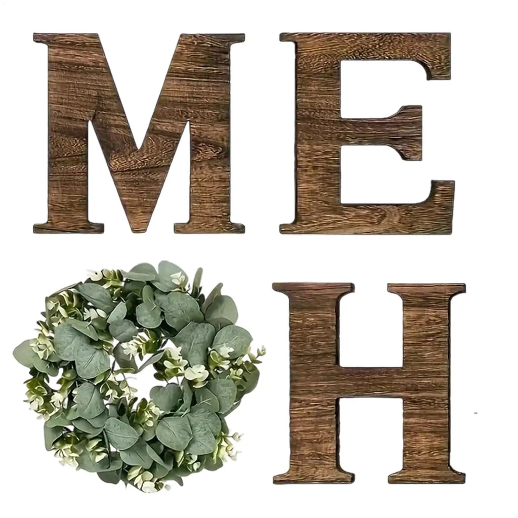 Rustic ‘HOME’ sign with dark brown wooden letters and an artificial eucalyptus wreath replacing the letter ‘O’.