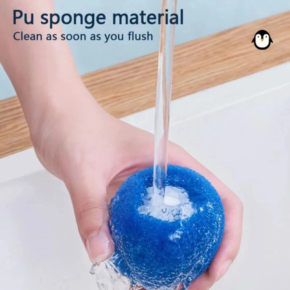 Hand holding a round, blue PU sponge being rinsed under a stream of water in a sink.