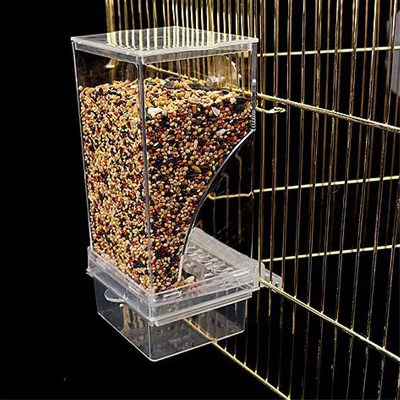 Clear acrylic bird cage feeder filled with multi-colored seeds, attached to gold vertical metal cage bars.