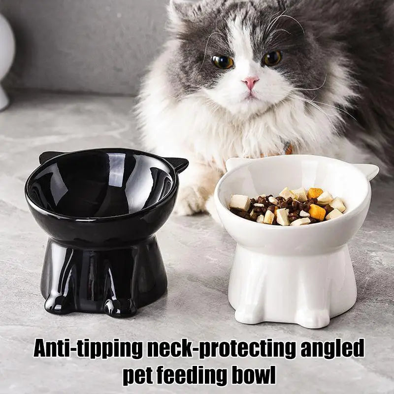 A fluffy cat behind black and white ceramic, cat-shaped, tilted elevated feeding bowls on a grey surface.