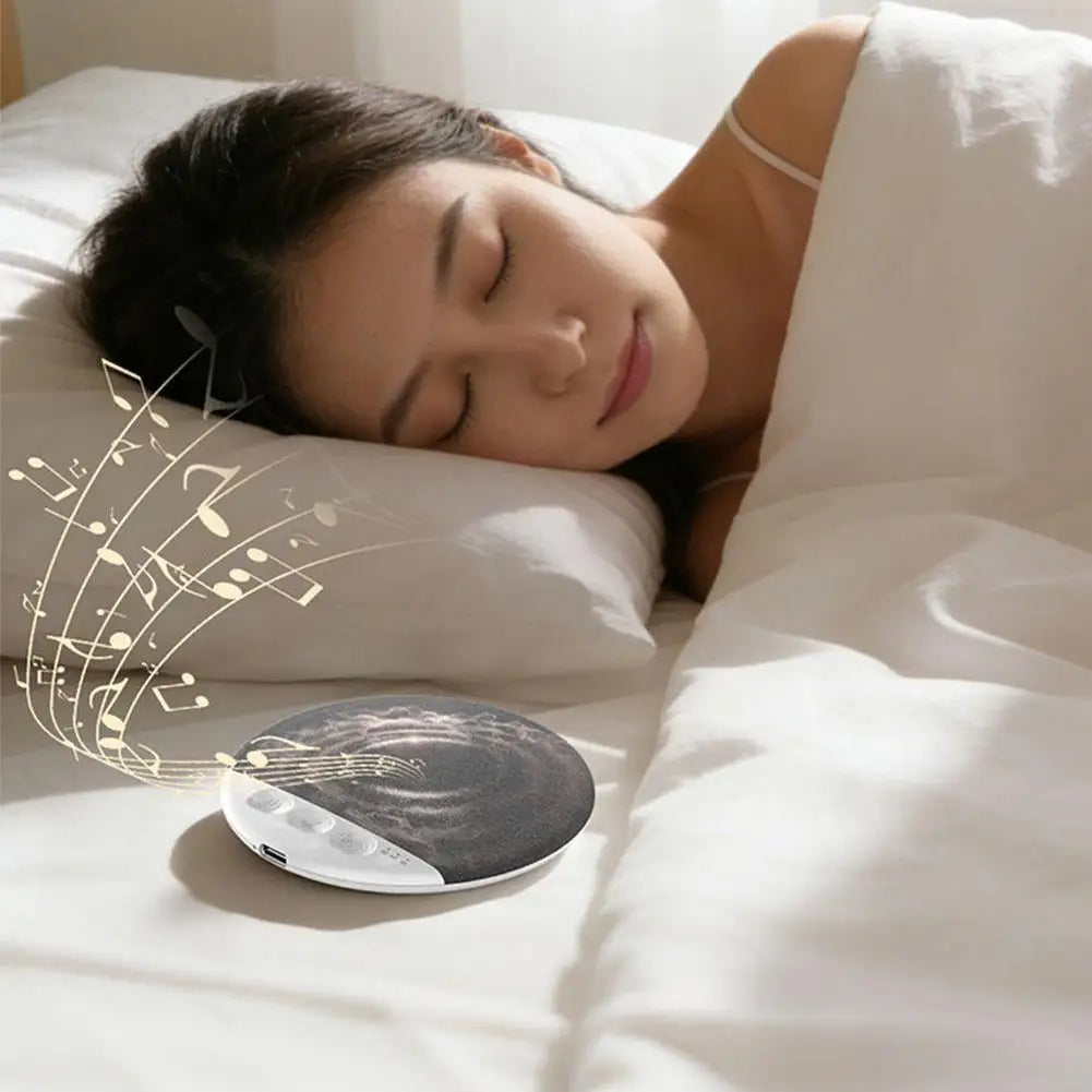 A woman sleeping beside a slim, circular, dark grey wireless Bluetooth sleep speaker with control buttons.