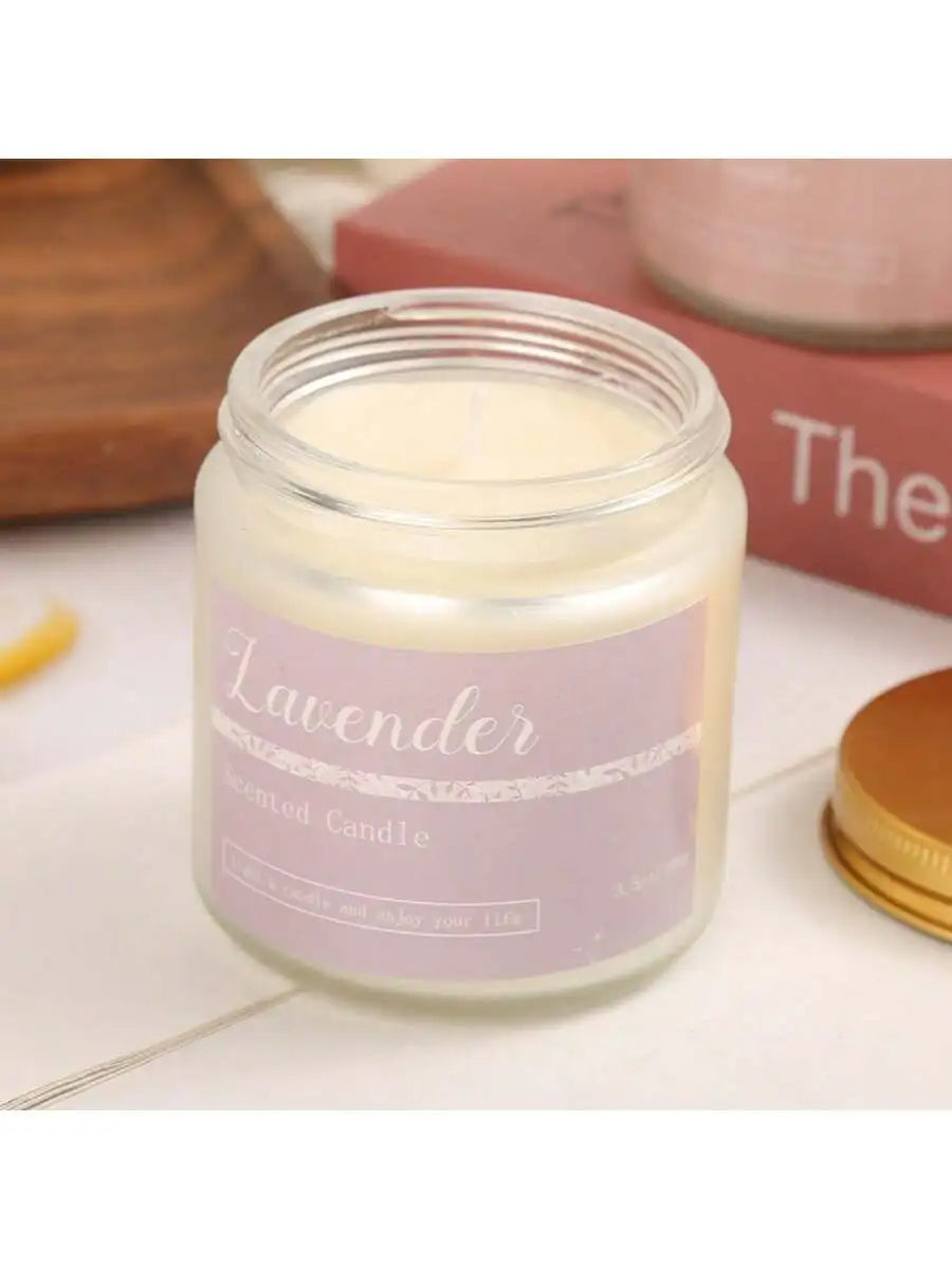 Lavender scented candle in a small glass jar with a purple label and separate gold metal lid.