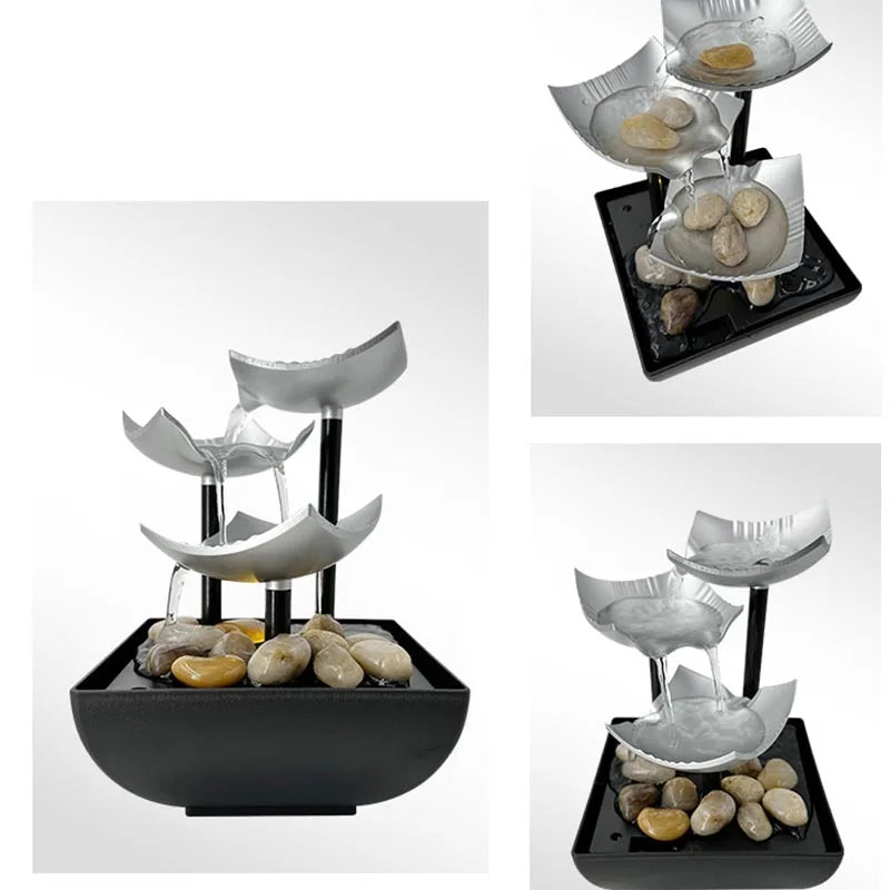 Modern tabletop fountain featuring three silver, bowl-shaped tiers, black supports, and decorative river stones.