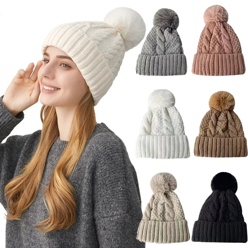 Woman wearing a cream cable-knit pom-pom beanie, with a selection of matching hats in various colours shown alongside.