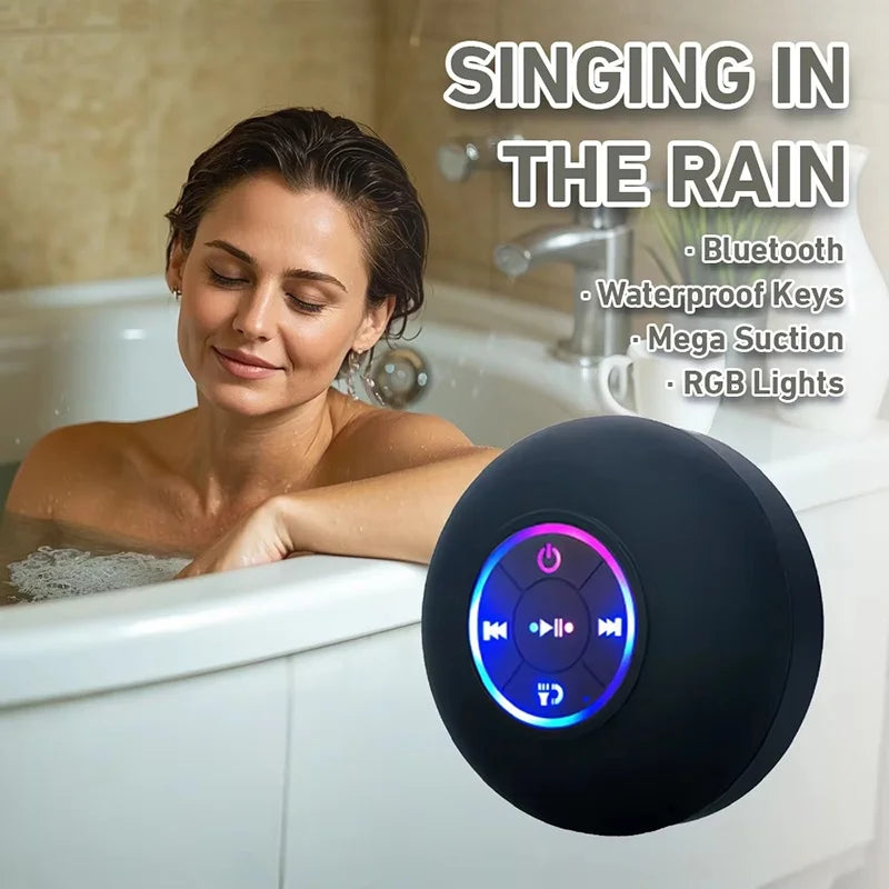 A black, circular waterproof Bluetooth speaker with glowing RGB light ring, shown in a bathroom setting.