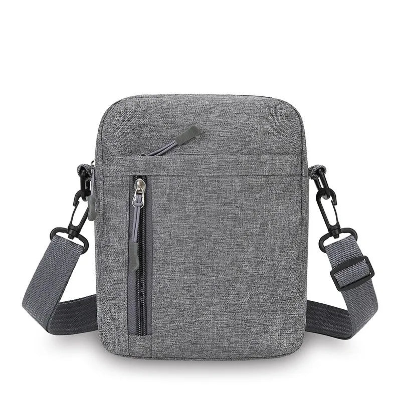 Grey fabric men's crossbody bag with an adjustable strap, top zip closure, and vertical front zipped pocket.