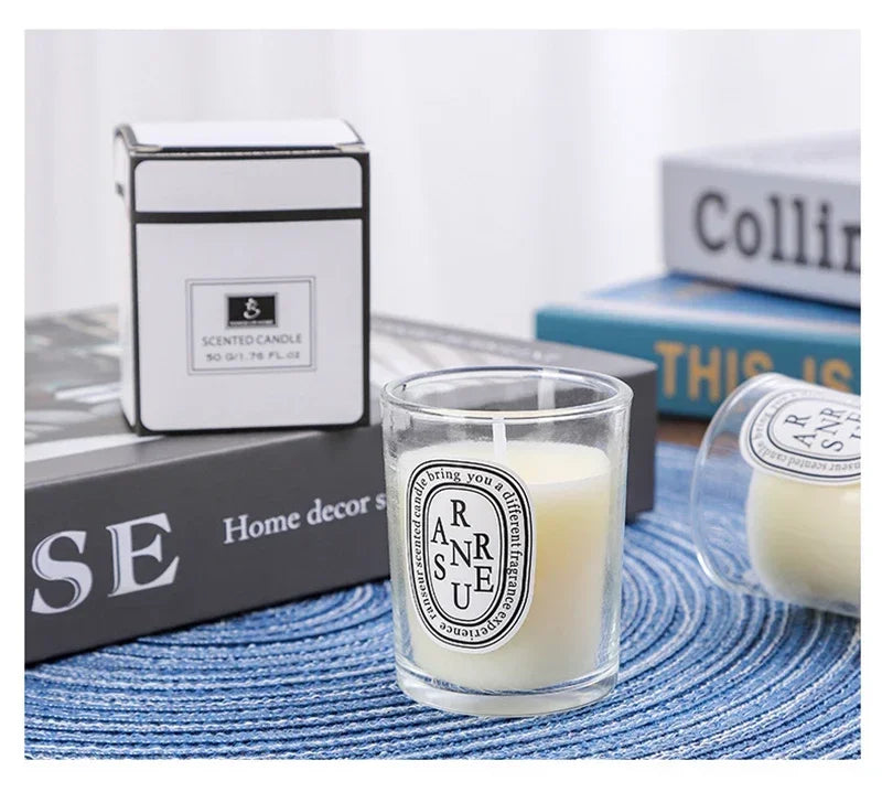 Small scented candle in a clear glass votive with a minimalist label, shown with its matching white gift box.