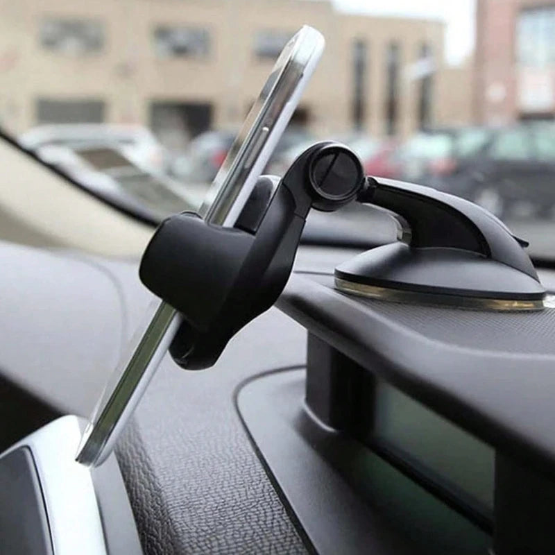 Black adjustable car phone mount with suction cup base attached to a vehicle dashboard holding a smartphone.